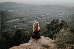 Woman sitting on a cliff staring at the scenery below